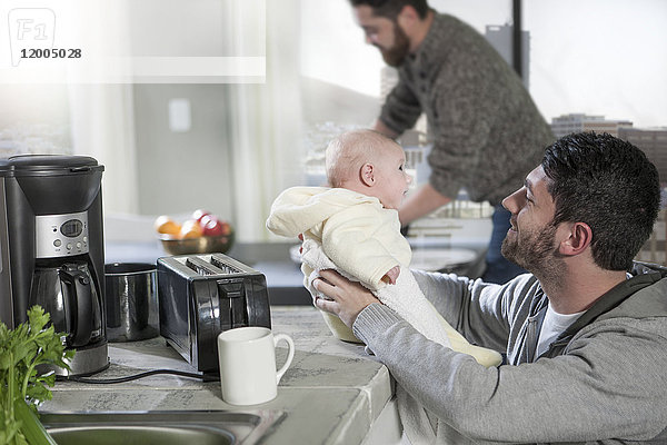 Zwei Männer mit Baby in der Küche