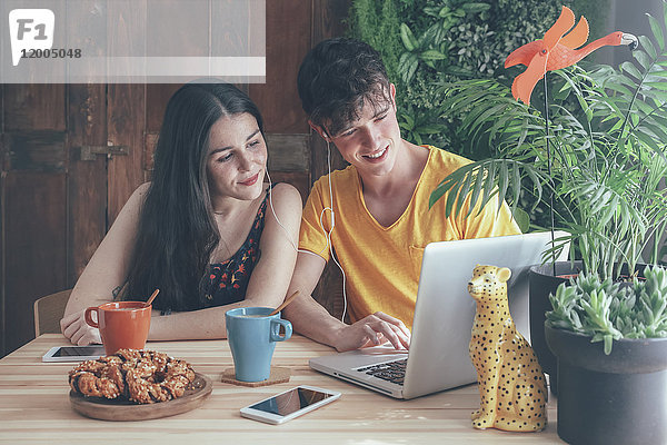 Junges Paar beim Kaffee- und Schokoladenzopf mit dem Laptop zu Hause