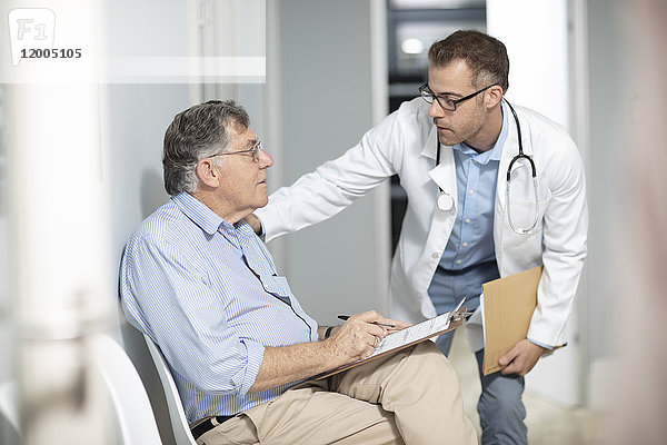 Arzt im Gespräch mit dem Patienten mit Akte in der Praxis