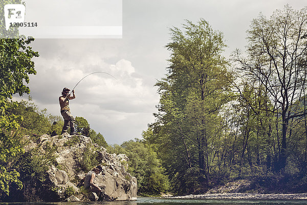 Slowenien  Mann Fliegenfischen im Fluss Soca auf einem Felsen stehend