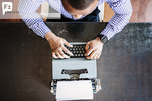 Junger Mann am Schreibtisch mit Schreibmaschine