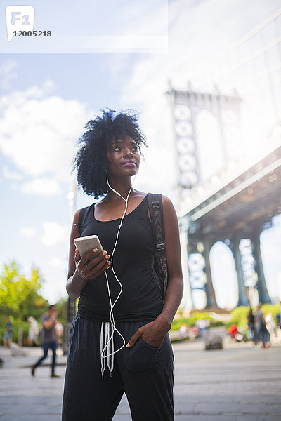 USA  New York City  Brooklyn  Frau beim Musikhören an der Manhattan Bridge