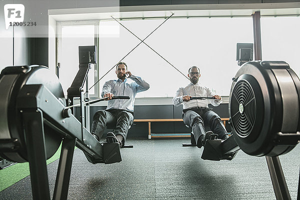 Geschäftsleute trainieren im Fitnessstudio  während sie telefonieren.
