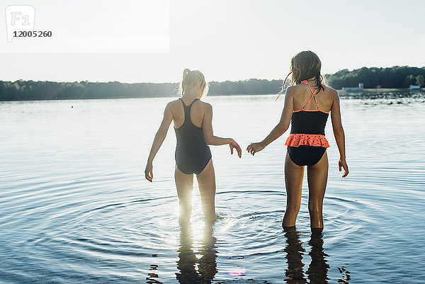 Rückansicht von zwei Freunden im Badeanzug am Seeufer