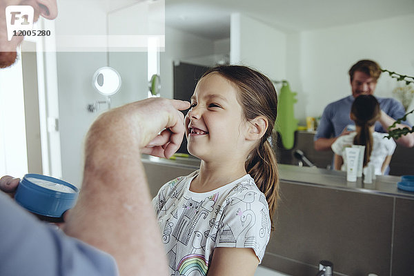 Vater legt Gesichtscreme auf das Gesicht der Tochter