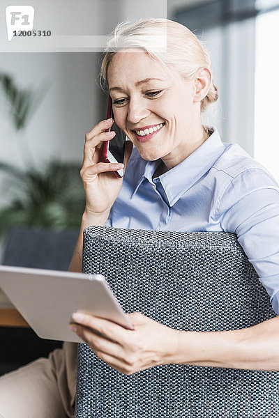 Lächelnde Geschäftsfrau am Telefon mit Tablette