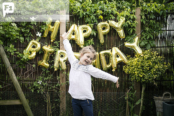 Portrait des Mädchens im Garten mit Dekoration für die Geburtstagsparty im Hintergrund