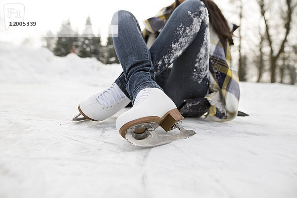 Frau mit Schlittschuhen auf Schnee liegend