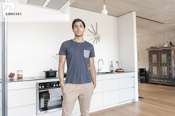 Junger Mann steht in der Küche zu Hause