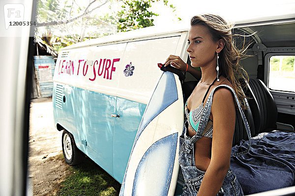 Porträt einer Frau mit Surfbrett im Van