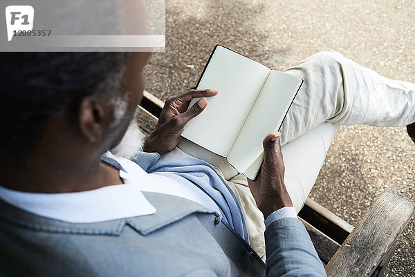 Mann liest auf Bank im Park  Teilansicht
