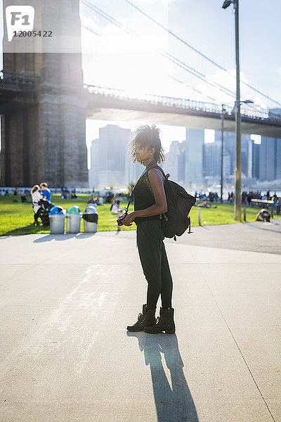 USA  New York City  Brooklyn  Frau mit Kamera stehend an der Brooklyn Bridge