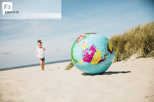 Globus am Strand mit Mädchen im Hintergrund