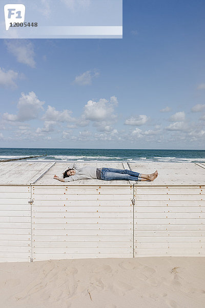 Frau auf Holzkiste am Strand liegend