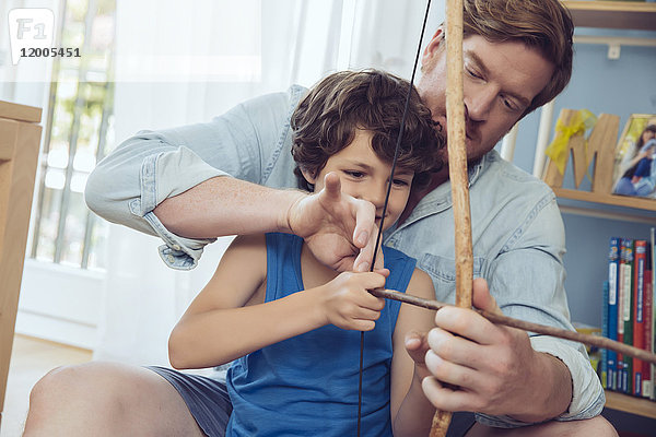 Vater zeigt dem Sohn  wie man selbstgemachten Pfeil und Bogen benutzt.