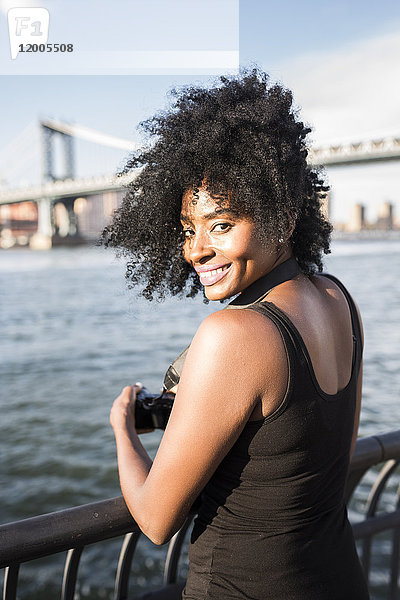 USA  New York City  Brooklyn  Porträt einer lächelnden Frau  die am Wasser steht