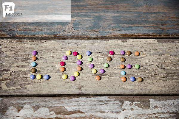 Schokoladentropfen bilden das Wort Liebe auf Holztisch