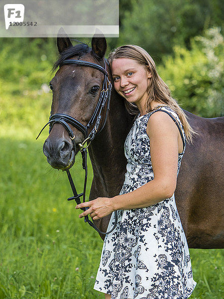 Lächelnde junge Frau und Pferd auf dem Feld