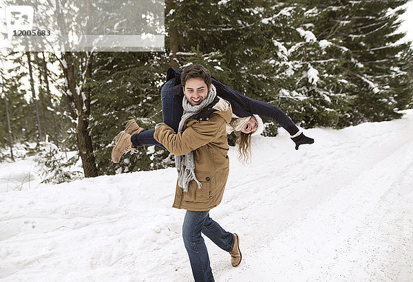 Glückliches junges Paar mit Spaß in verschneiter Winterlandschaft