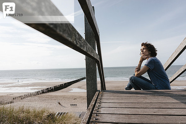 Frau sitzt auf einer Strandpromenade am Strand
