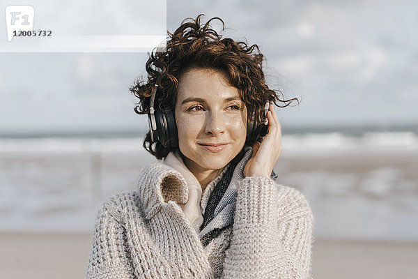 Lächelnde Frau am Strand mit Kopfhörer