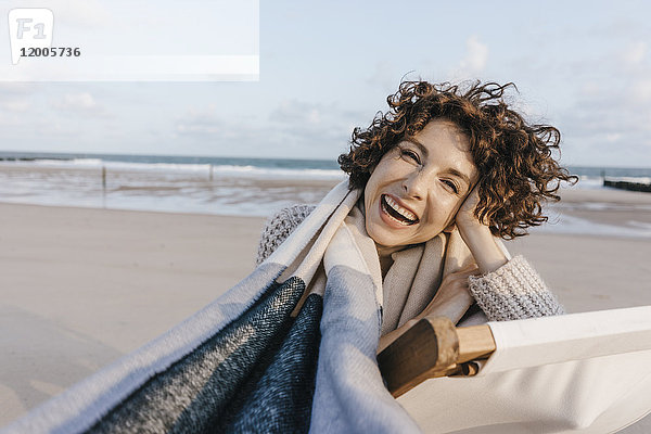 Porträt der glücklichen Frau im Liegestuhl am Strand