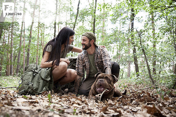 Paar mit Rucksack und Hund im Wald
