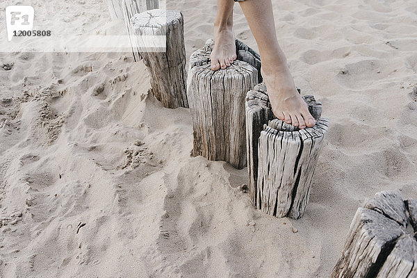 Frauenfüße auf Holzpflöcken am Strand