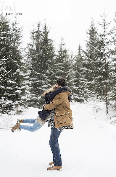 Fröhliches junges Paar beim Spaß im verschneiten Winterwald