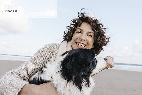 Glückliche Frau mit Hund am Strand