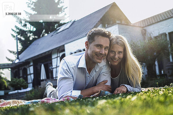 Ein glückliches Paar liegt auf Gras im Garten ihres Landhauses.