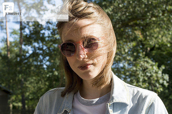 Porträt einer jungen Frau in der Natur mit Sonnenbrille