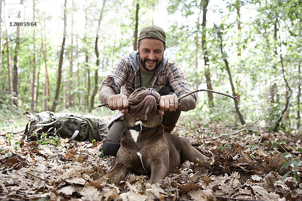 Mann spielt mit Hund im Wald