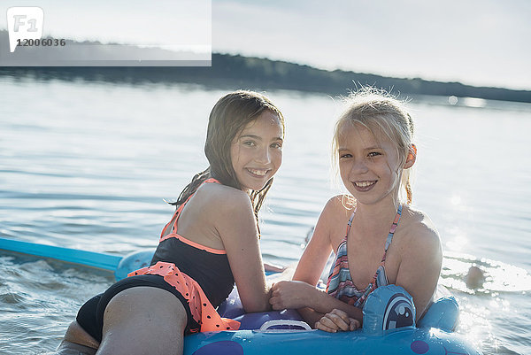 Portrait von zwei Mädchen mit Schwimmspielzeug am See