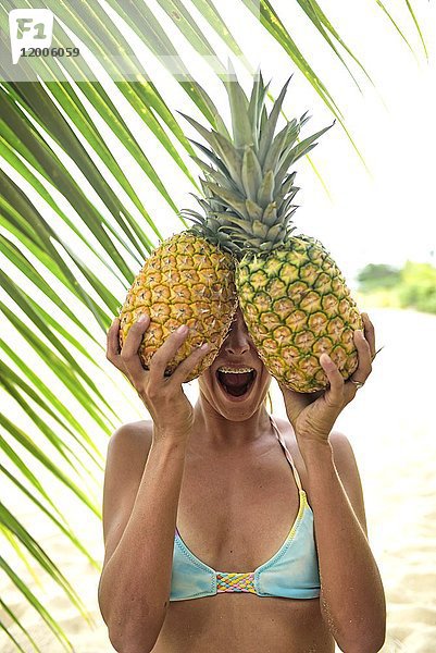 Junge Frau mit zwei Ananas an der Palme