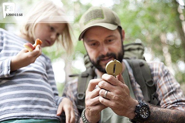 Vater zeigt Kompass an Tochter im Wald