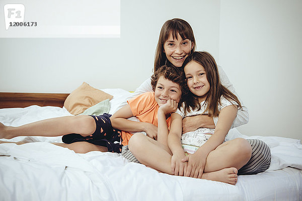 Glückliche Mutter im Bett mit Tochter und Sohn