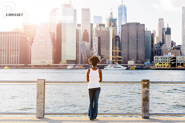 USA  New York City  Brooklyn  Frau am Wasser mit Blick auf die Skyline