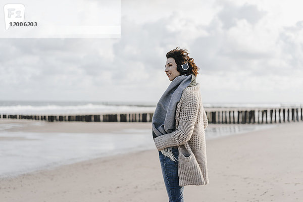 Frau am Strand stehend mit Kopfhörer