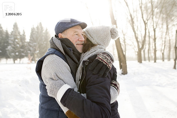 Glückliches Seniorenpaar beim Umarmen in der Winterlandschaft