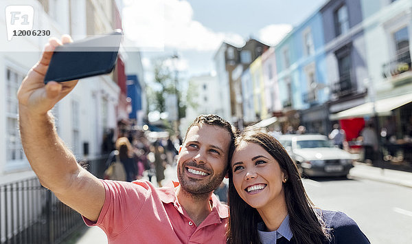 UK  London  Portobello Road  glückliches Paar nimmt Selfie mit Handy