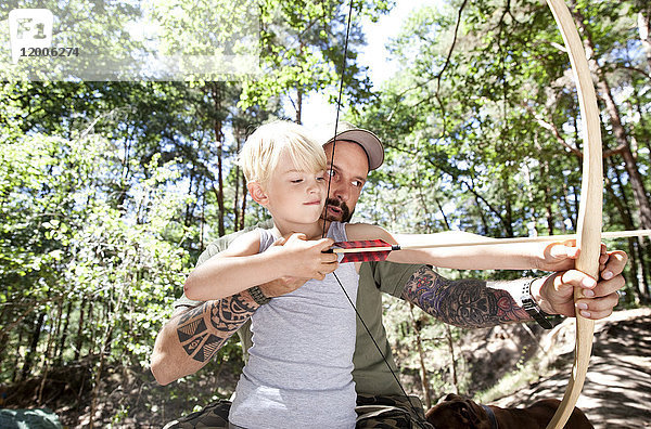 Vater und Sohn schießen mit Pfeil und Bogen im Wald