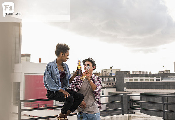 Junges Paar klirrende Bierflaschen auf dem Dach