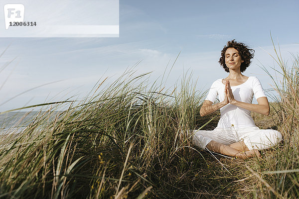 Frau beim Yoga in der Stranddüne