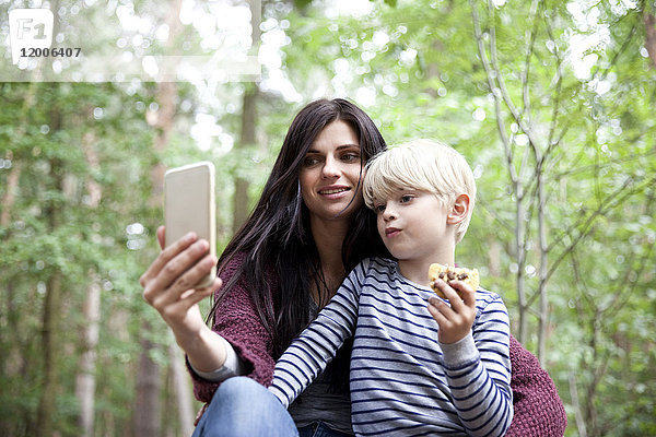 Mutter und Sohn nehmen einen Selfie im Wald.