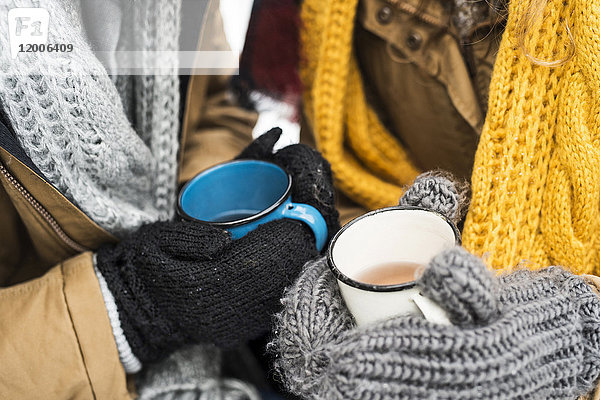 Junges Paar mit Handschuhen und Tassen Tee im Winter  Nahaufnahme