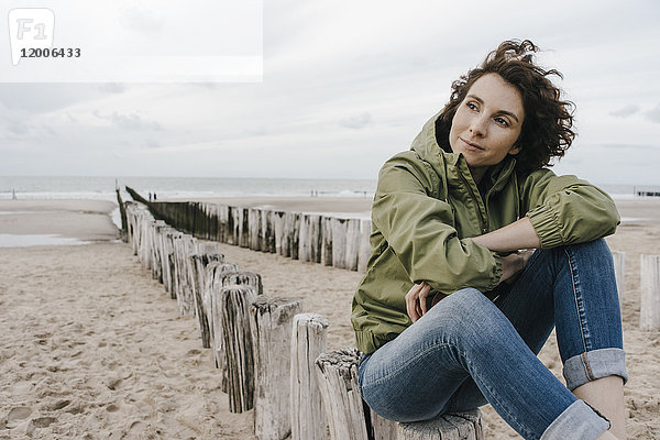 Frau auf Holzpfahl am Strand sitzend