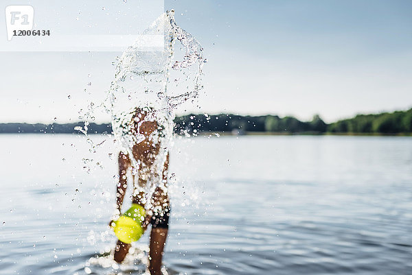 Junge spritzt mit Wasser am Seeufer  Nahaufnahme