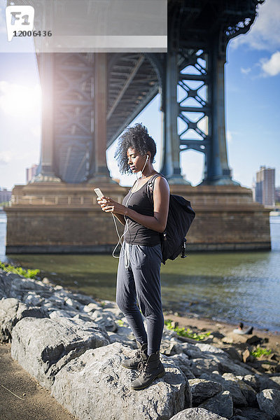 USA  New York City  Brooklyn  Frau beim Musikhören unter der Manhattan Bridge