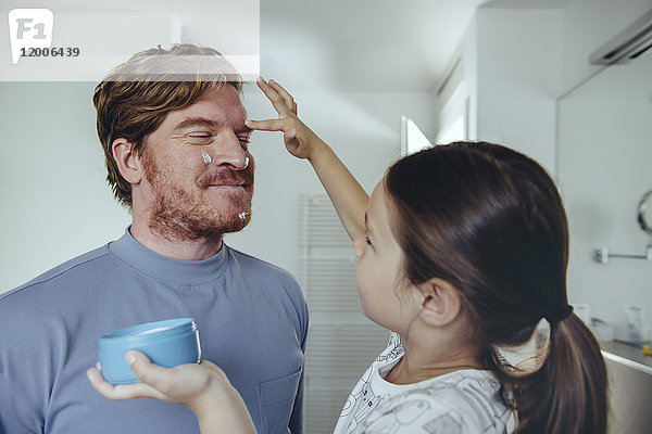 Tochter legt Gesichtscreme auf Vaters Gesicht